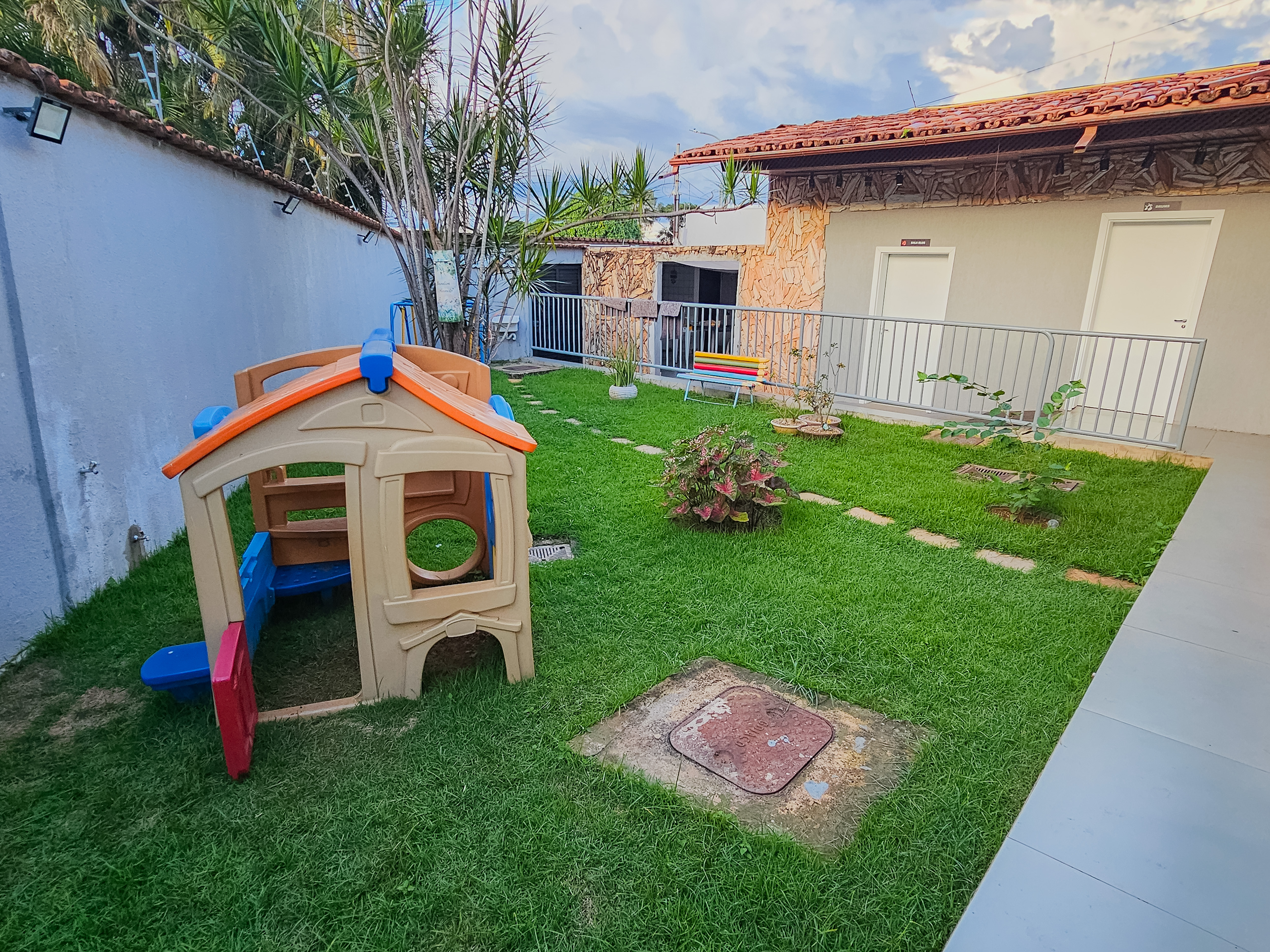 Jardim externo da escola com gramado e área de lazer
